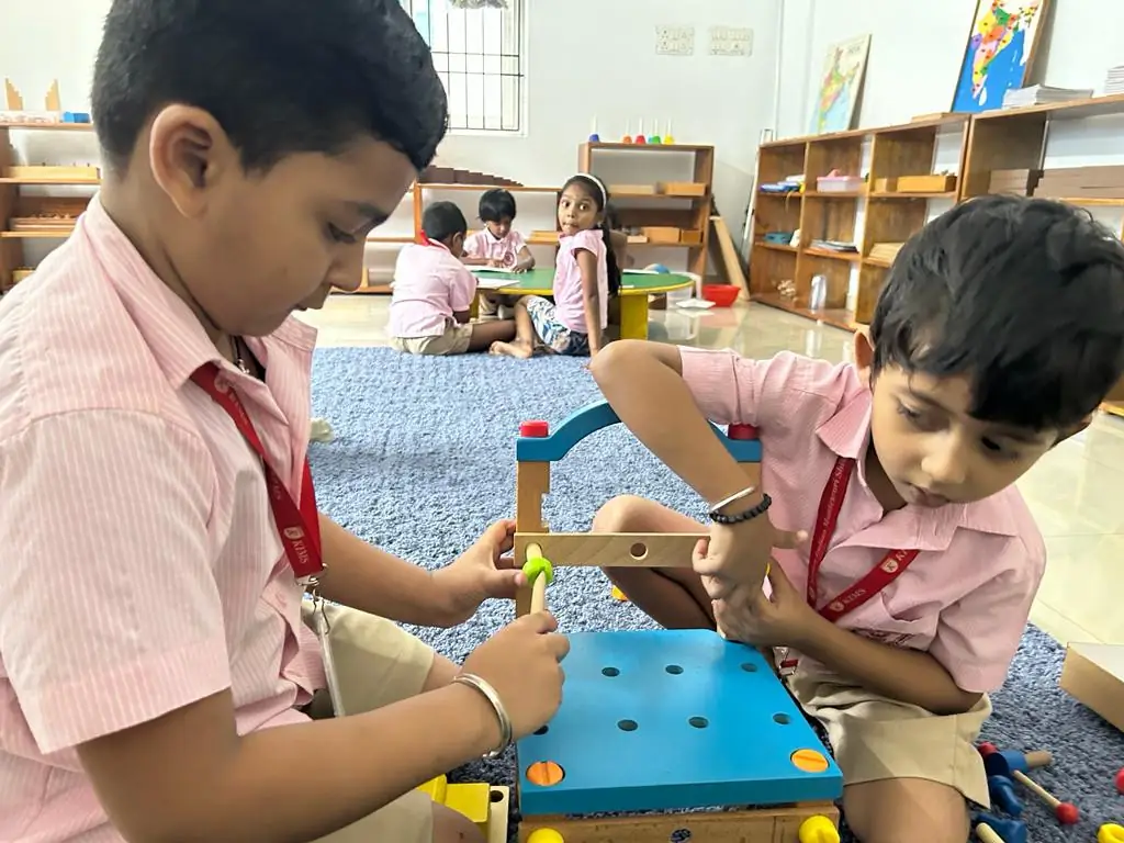Two KIMS boys working together with a Montessori construction set